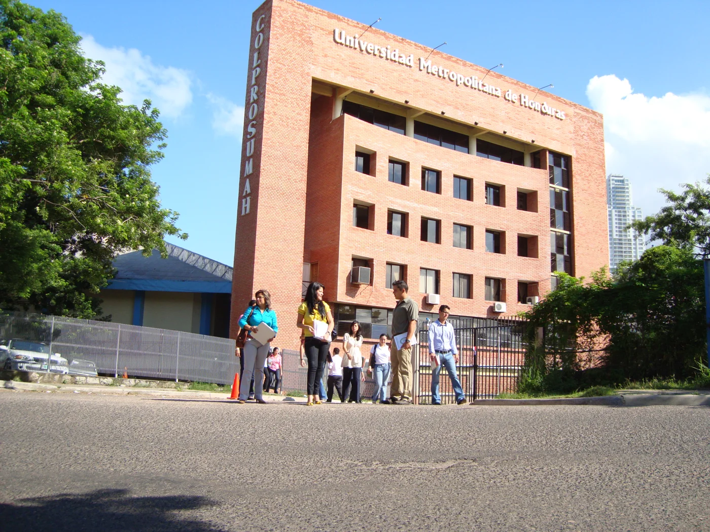 Edificio del primer campus de la UMH visto desde la calle, con estudiantes frente a la entrada